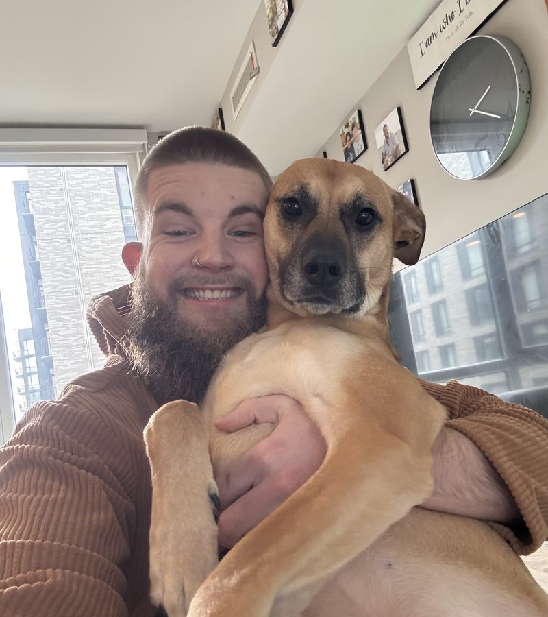 Caleb Johnston smiling while holding one of his dogs.